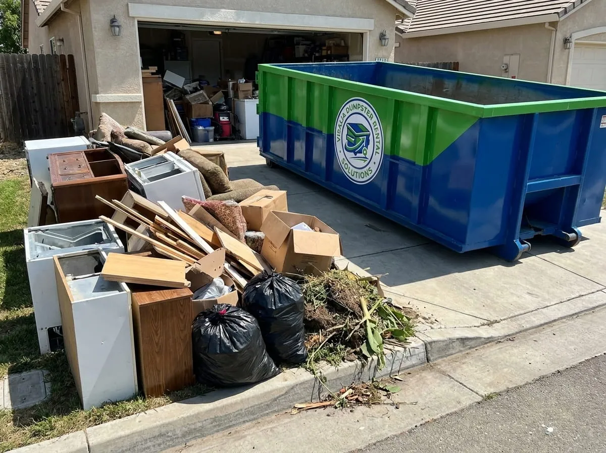 Roll-off container beside a large household clearance pile in Visalia, California